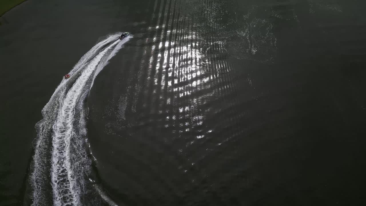 Aerial over a jet ski towing a person on an inflatable tube on the waters off Santa Catarina Island in the State of Santa Catarina, Brazil