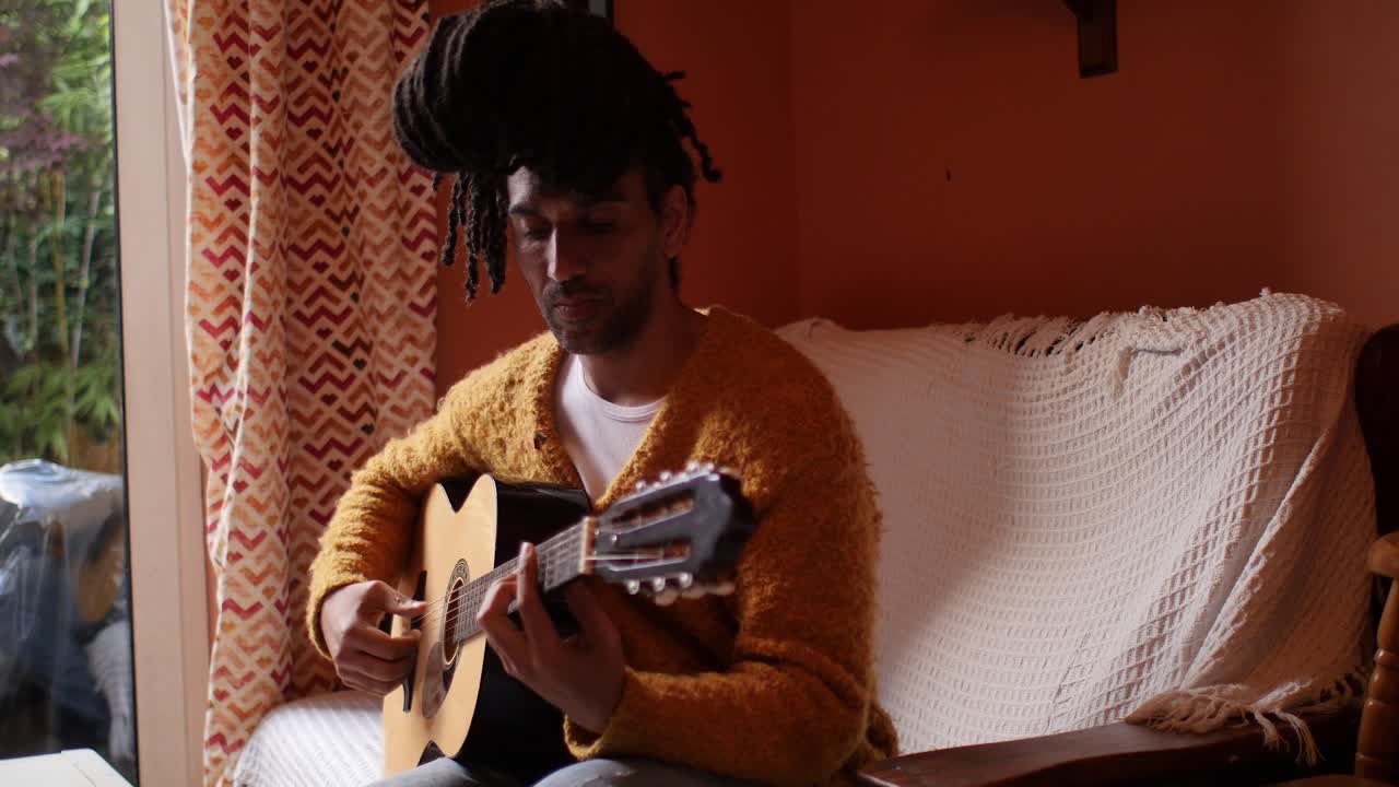Modella afro elegante che suona la chitarra in soggiorno