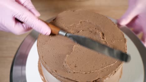 pastry chef woman is smearing chocolate cream on sponge cake