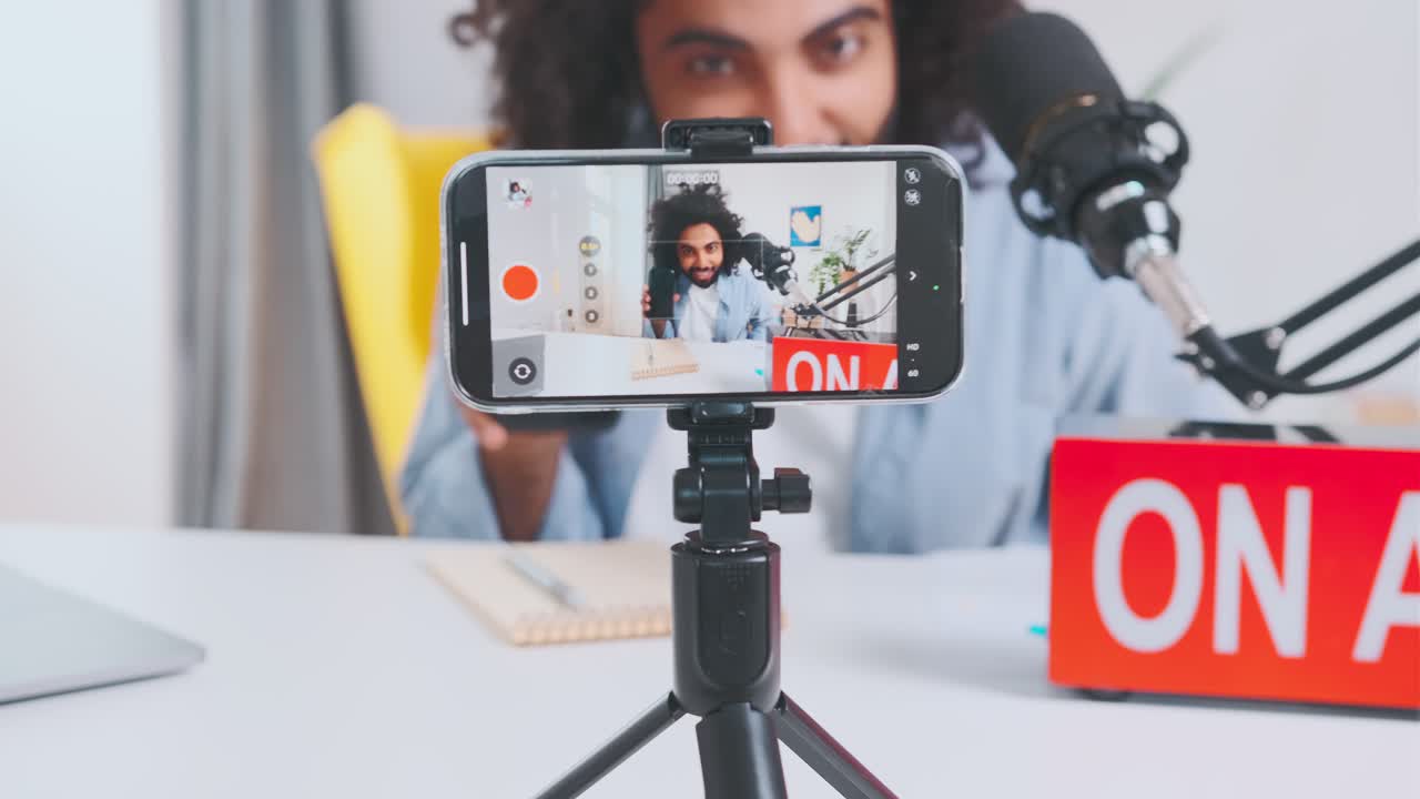 joven árabe positivo registra un blog con anuncios de teléfonos inteligentes en la cámara del teléfono