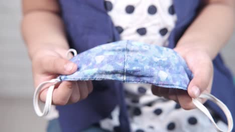 niño con una máscara facial de tela con patrón azul