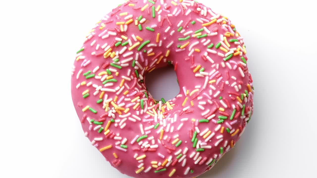 primer plano rosado donut con pastel de tapa giratorio vista superior aislada. disparado con cámara roja en 4k