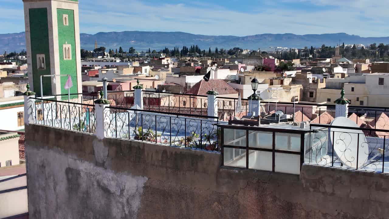 A view from a rooftop overlooking Meknes, showing the Great Mosque and surrounding cityscape