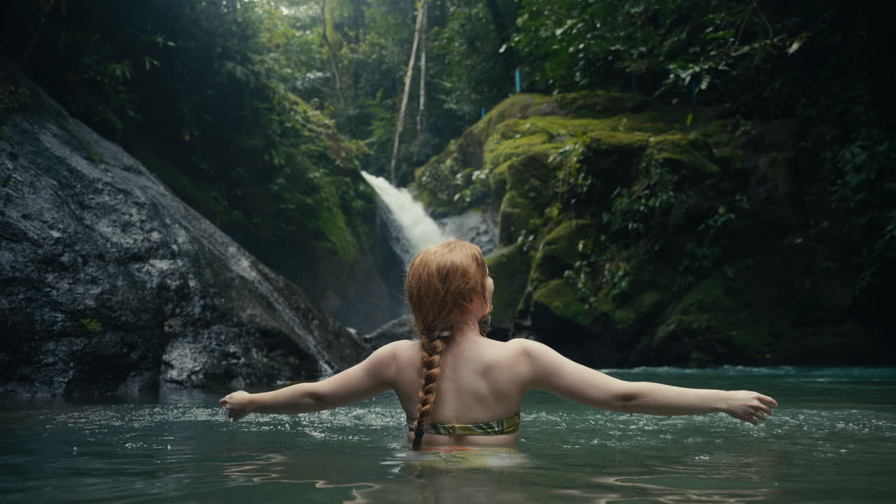Woman enjoying a waterfall in a lush forest