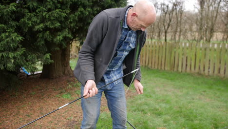 a mature man putting tent poles together at a campsite whist camping