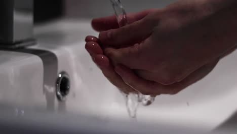 Person-washing-their-hands-under-a-running-tap