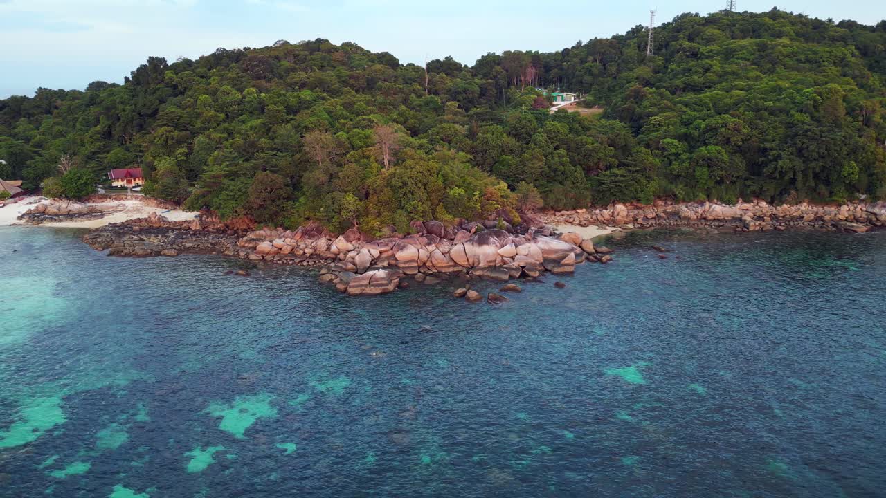 Capturing the beauty of a tropical island, turquoise waters and rocky coastline, this aerial view shows vibrant blue and green hues against rugged cliffs and shores
