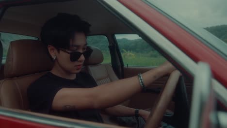 man driving a vintage red car