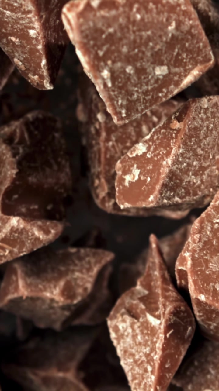 Primo piano al rallentatore di pezzi di cioccolato e polvere che cadono