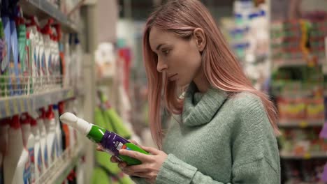 woman buying household products in supermarket, reads label