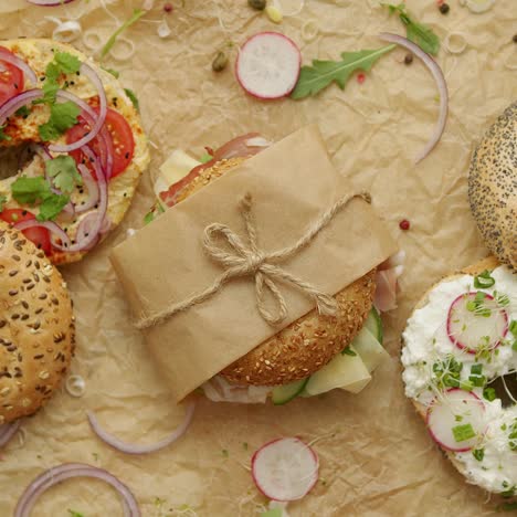 bagels with ham  cream cheese  hummus  radish wrapped in brown baking paper ready for take away