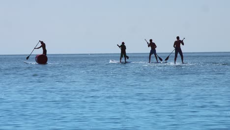 Group-surfer-man-stand-up-paddle-board-and-riding-on-sea-at-summer-vacation