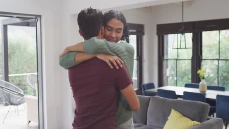 feliz pareja masculina diversa abrazando y sonriendo en la sala de estar