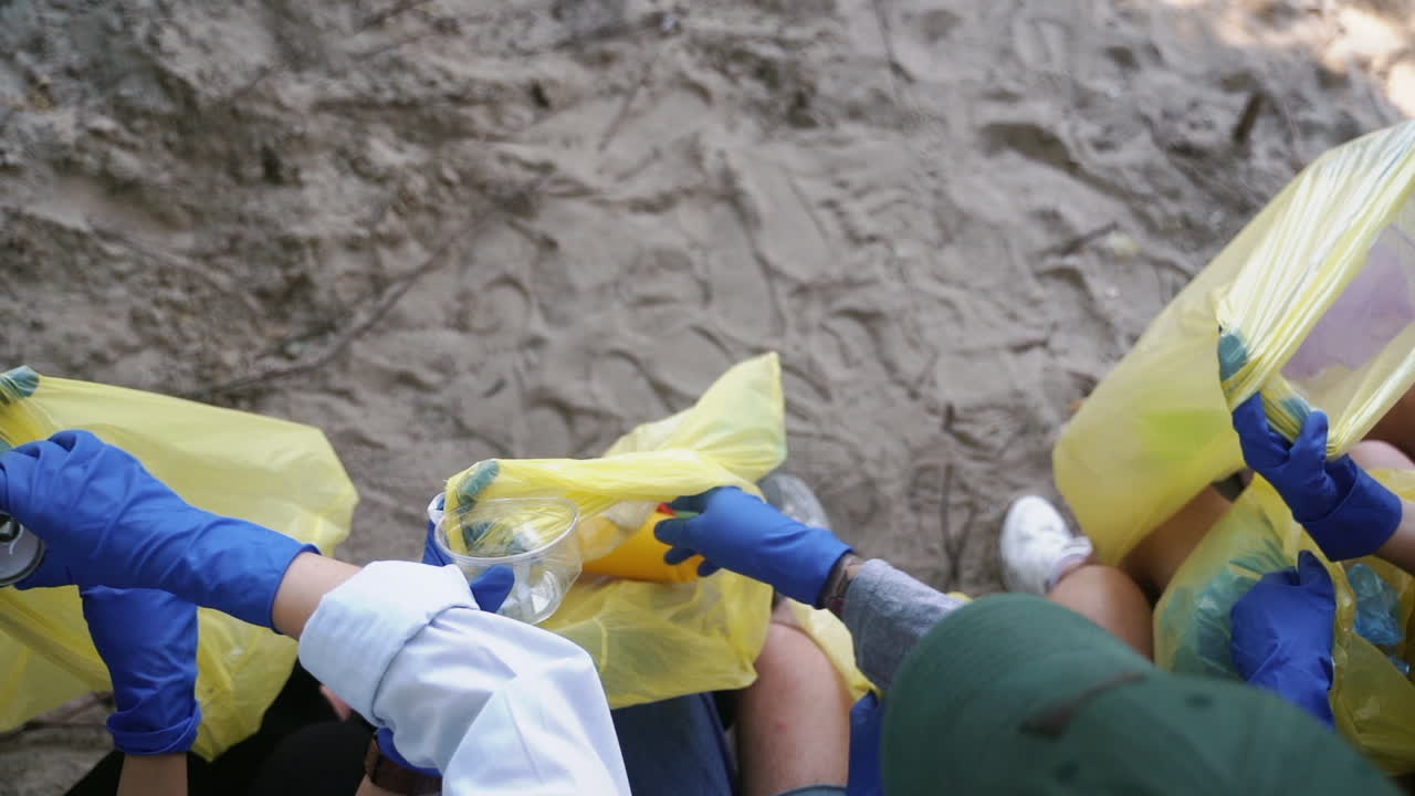 자원 봉사자 들 이 모래 환경 을 청소 하고 있다