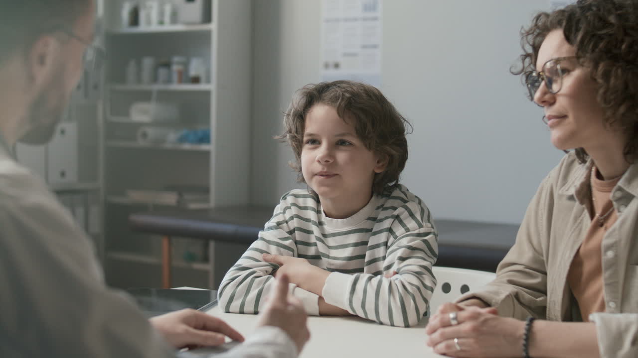 Bambino e sua madre che parlano con il medico nell'ambulatorio medico