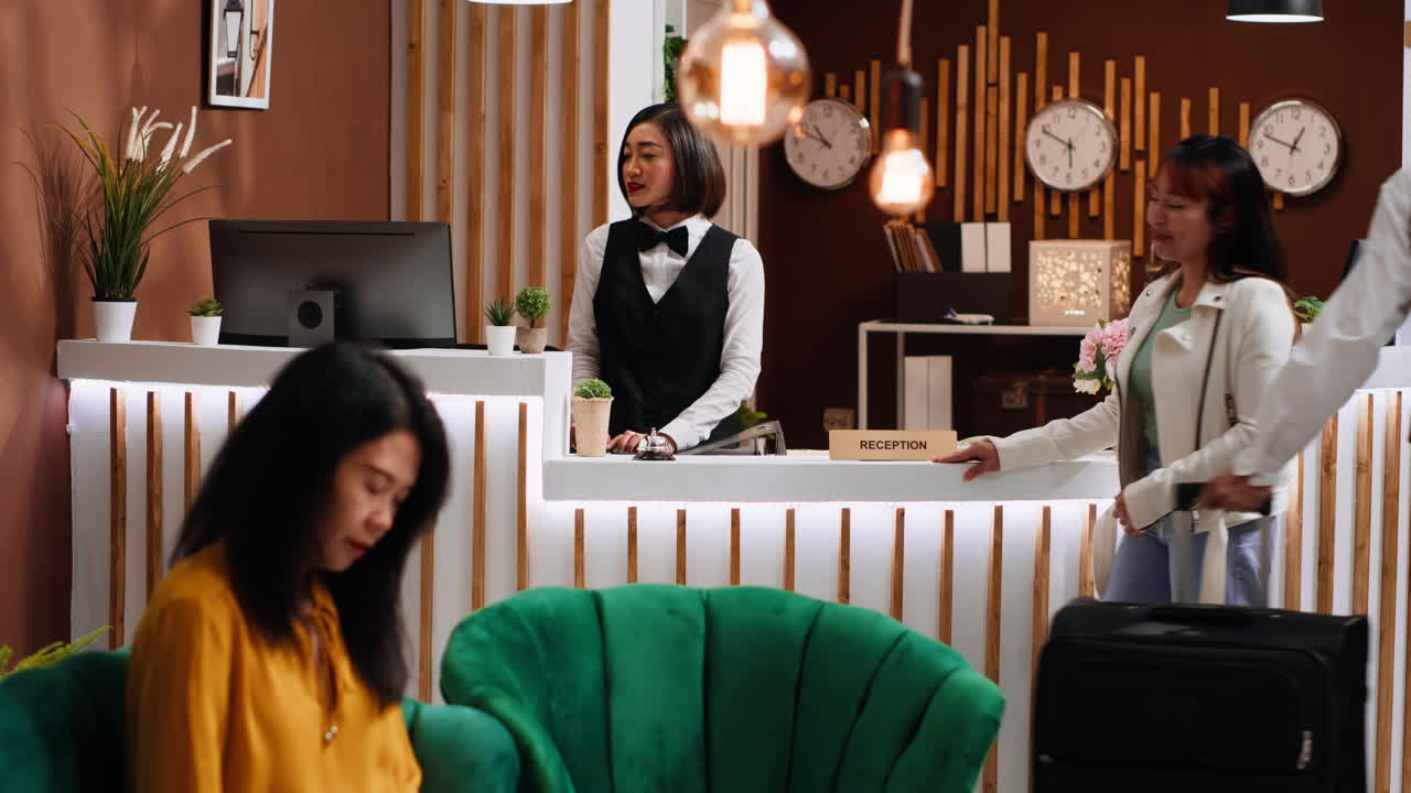 Un cliente asiatico arriva alla reception con dei sacchetti da carrello.