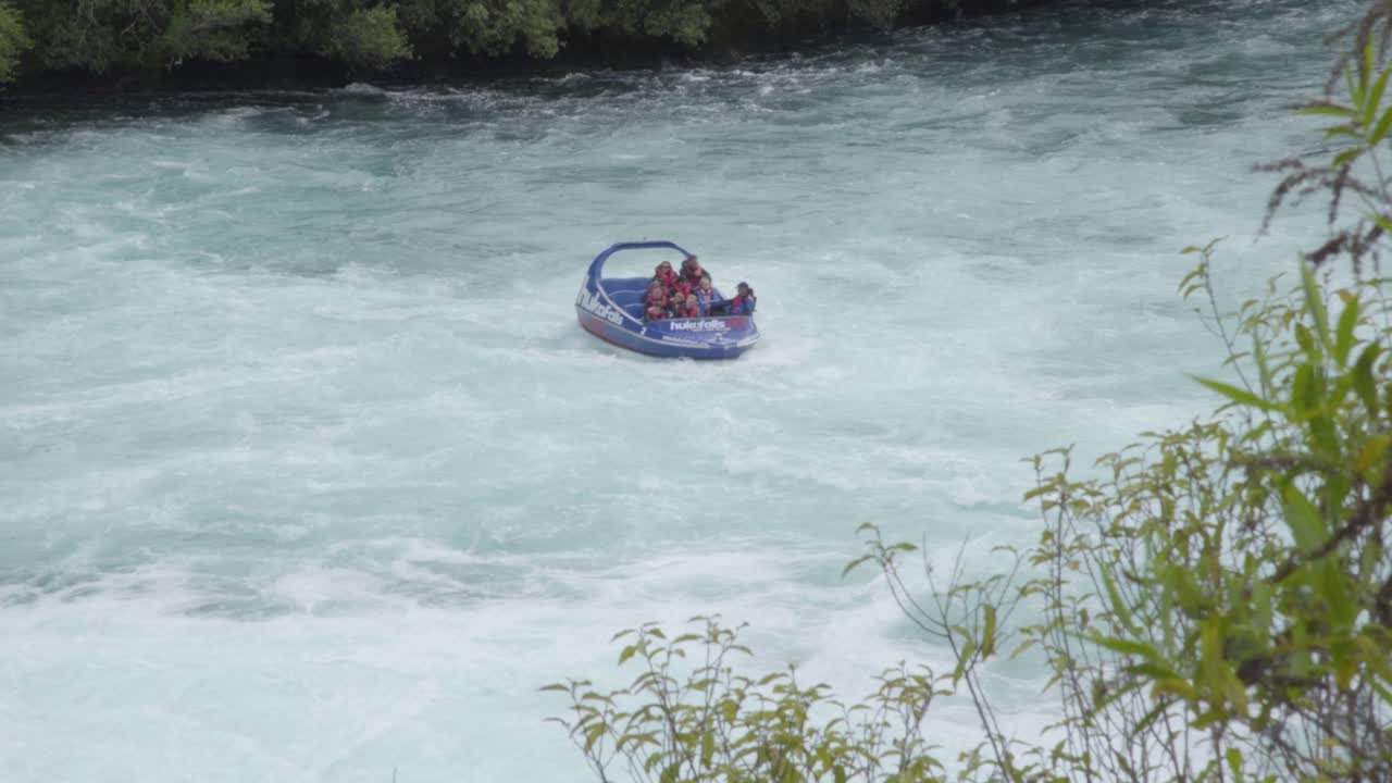 A shot of people in the Huka Falls jet boat as moves back and forth in white water before leaving frame