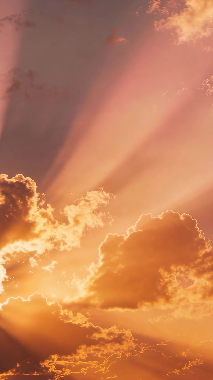 Vertical video: Sun low left backlit cumulus bank, clouds glowing, casting rays at dusk, dark band