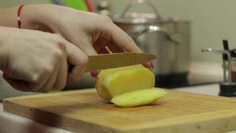 female housewife hands slicing potatoes into pieces in the kitchen