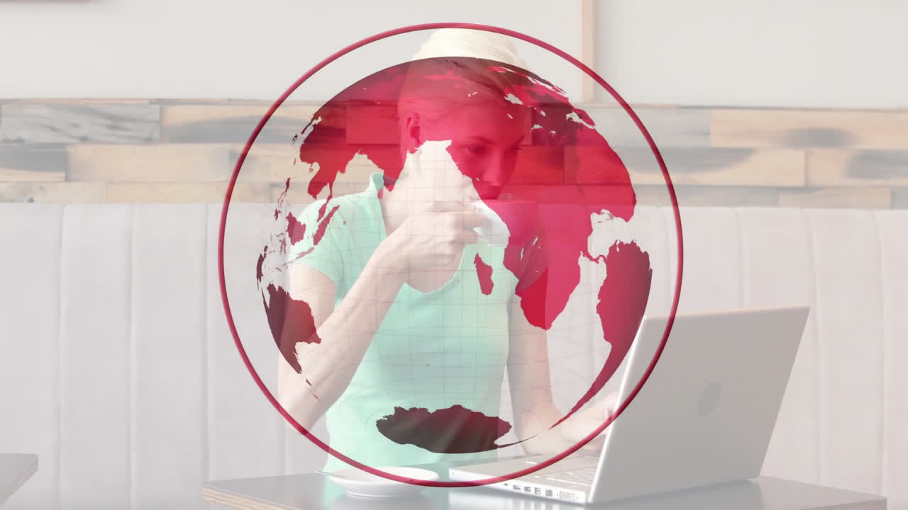 woman sipping coffee while working on laptop in cafe, interacting with red globe business graphic