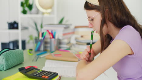 young student writes in a notebook, does her homework and studies for school