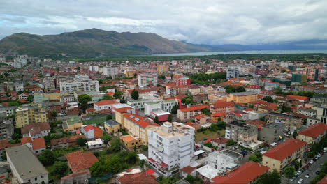 Aerial-drone-forward-moving-shot-over-city-buildings-and-houses-alongside-roads-in-Shkoder-or-Scutari-in-northwestern-Albania-on-a-cloudy-day