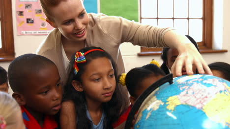 Teacher-looking-at-globe-with-pupils