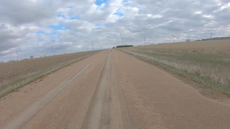 rear window view while driving around a curve on a gravel road thru rural nebraska on a cloudy winter day