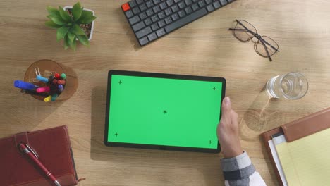 vista aérea de una persona trabajando en una tableta con una pantalla verde