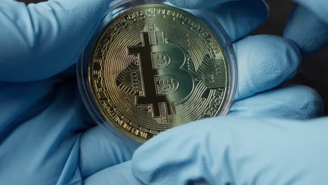 Hand-Mit-Handschuhen-öffnet-Einen-Behälter-Mit-Einer-Bitcoin-Kryptowährung-Darin