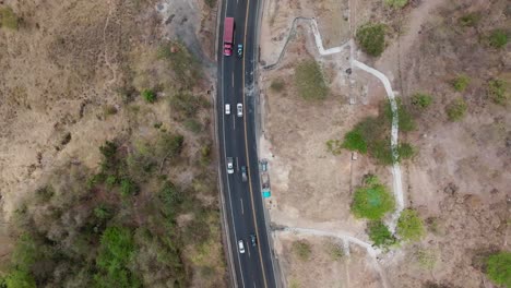 vista aérea de un avión no tripulado: una autopista sinuosa que atraviesa un terreno árido, una vegetación escasa, vehículos en la carretera