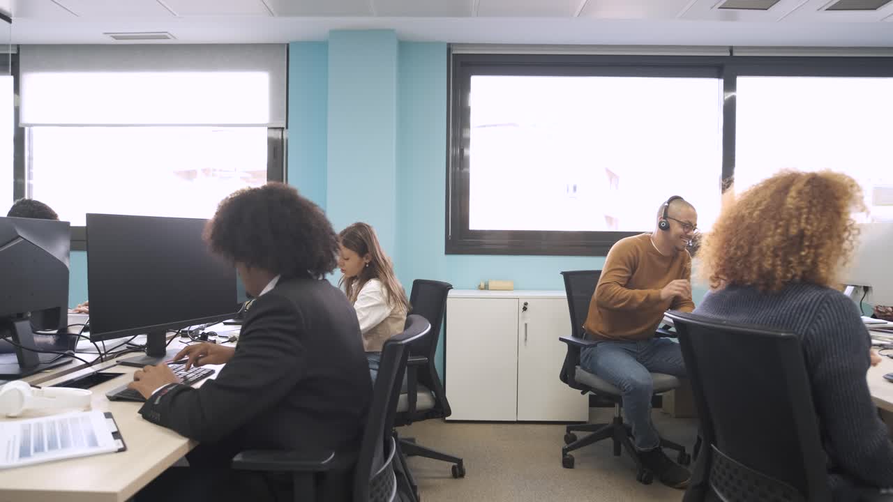 Happy multiethnic colleagues discussing and working on computers in creative workspace