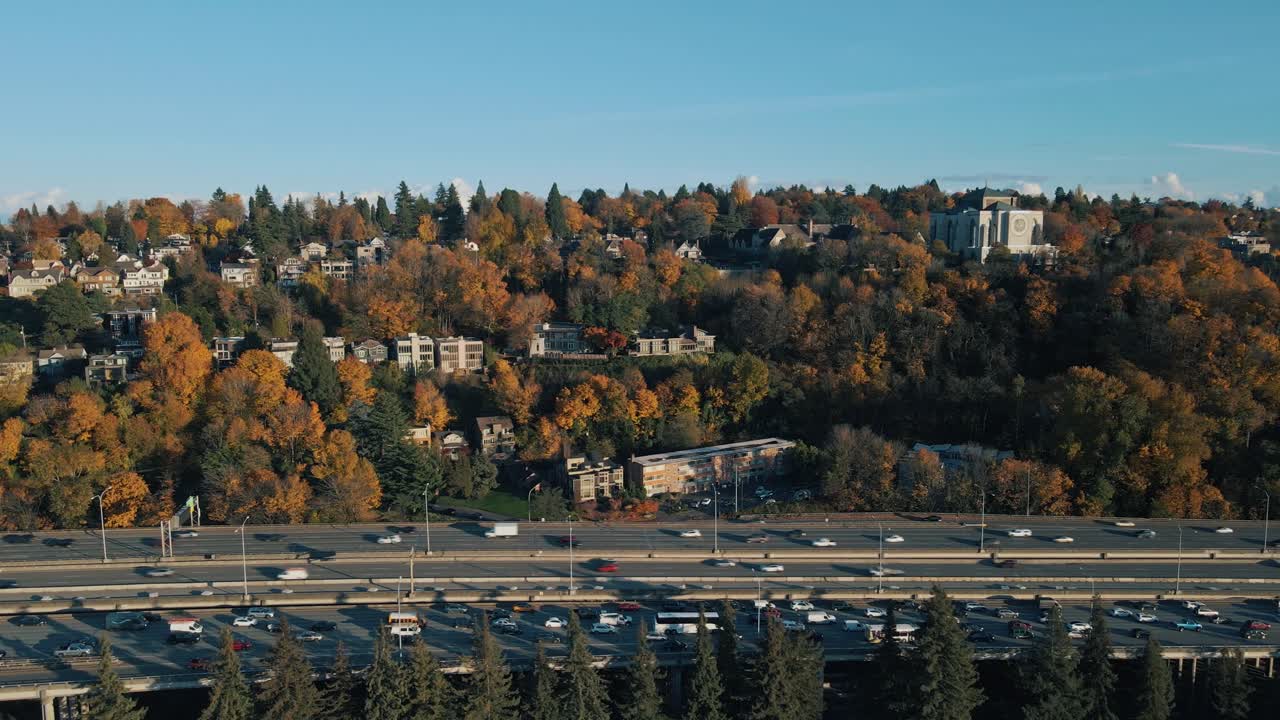 panorámica aérea a través de naranja vibrante rojo caída árboles de colores alineando el tráfico y la carretera ocupada en seattle washington