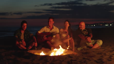 friends enjoying a bonfire on the beach at night