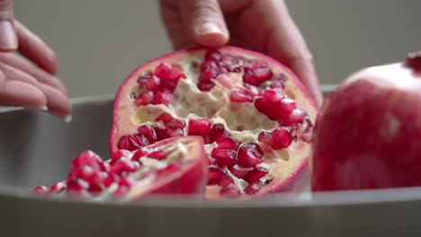 close up of opening up a big red pomegranate sitting on white plate on table healthy anti-oxidants cardioprotective properties