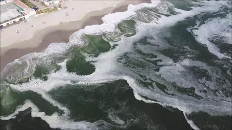 Top-down-drone-shot-of-the-ocean,-sand-and-beach-houses-in-Peru