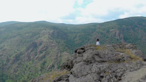 aerial view, drone fly over the seated girl on a cliff face