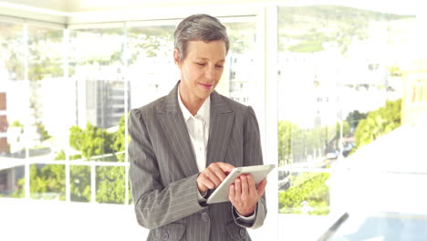 Confident-businesswoman-using-tablet-and-looking-at-camera