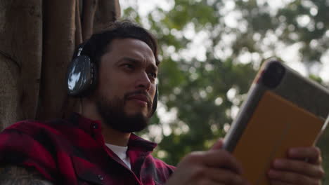 man relaxing outdoors with headphones and tablet