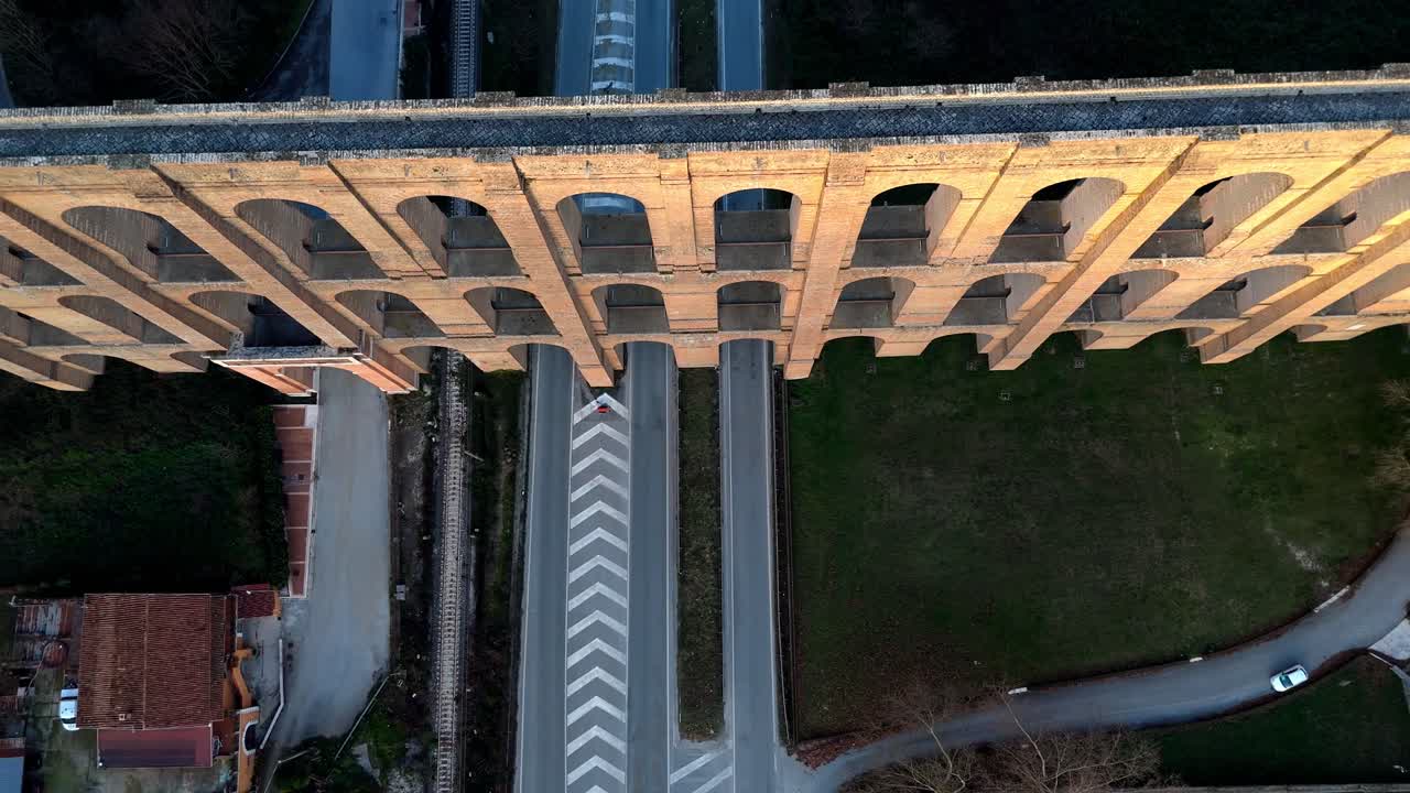 Vista aerea zenitale con drone dell'Acquedotto Carolino al tramonto, con la calda luce dorata che illumina gli storici archi di pietra a Caserta, Italia.