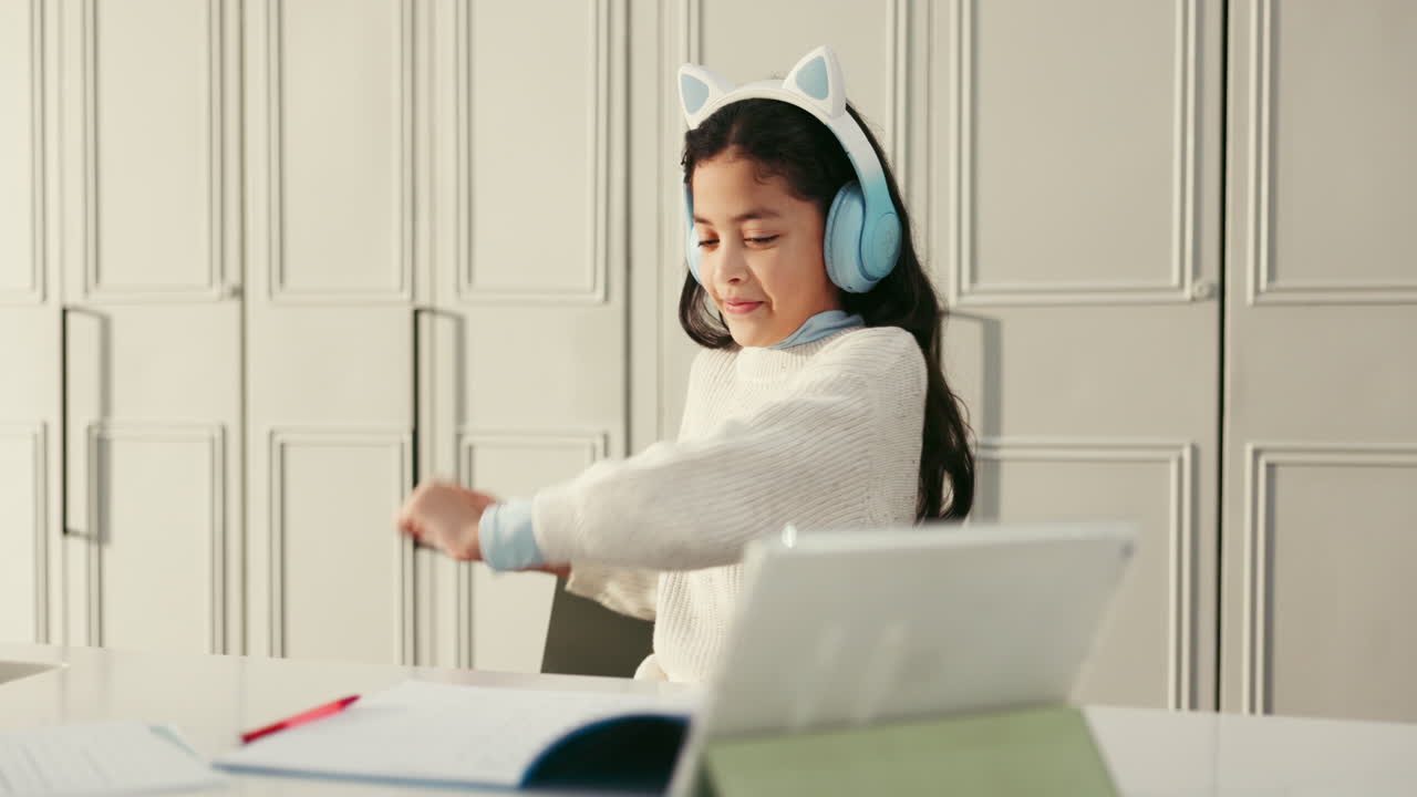 Girl with cat ear headphones studying at desk with tablet