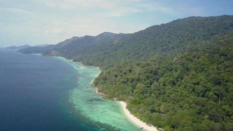 vista aérea de una larga isla exuberante con vegetación y hermosas aguas en tailandia - disparo de seguimiento lateral ligeramente panorámico a la izquierda
