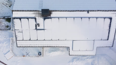 Aerial-top-down-shot-rising-above-solar-cells-on-a-melting-house-roof,-winter-day