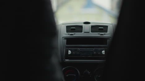 back view of driver turning steering wheel to navigate urban street corner, blurred cars passing outside windows, focus on hands gripping wheel and dashboard, capturing commuter journey in motion