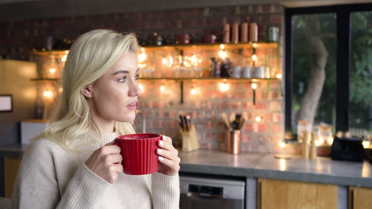 Entering home kitchen, woman holding red mug, gazing out window, seeking quiet reflection