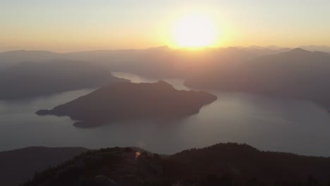 fast panning aerial drone from deeks peak at sunset showing fjord with island and mountain landscape pacific ranges canada bc 4k