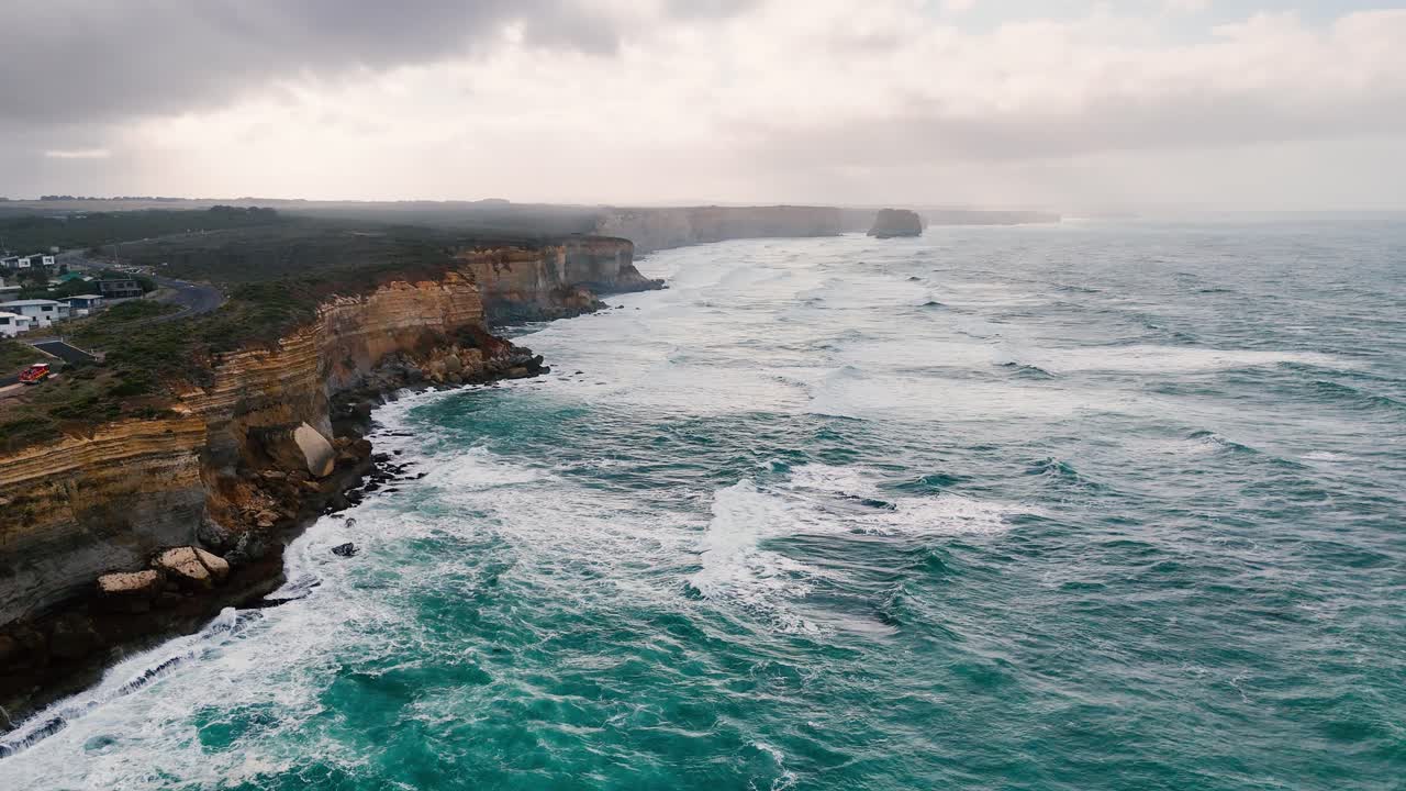 Drone footage captures the rugged cliffs and turbulent sea along Australia's Great Ocean Road under overcast skies