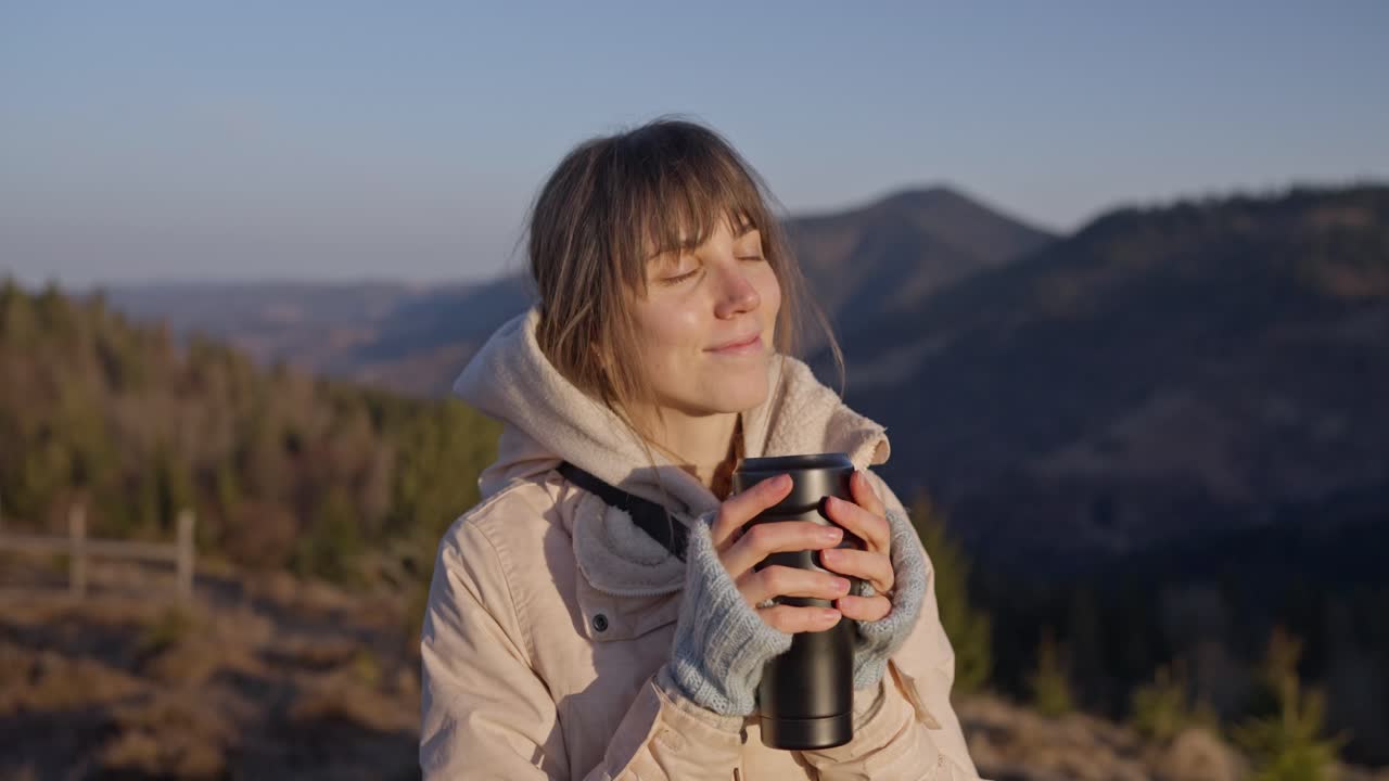 Woman enjoying a hot drink in the mountains