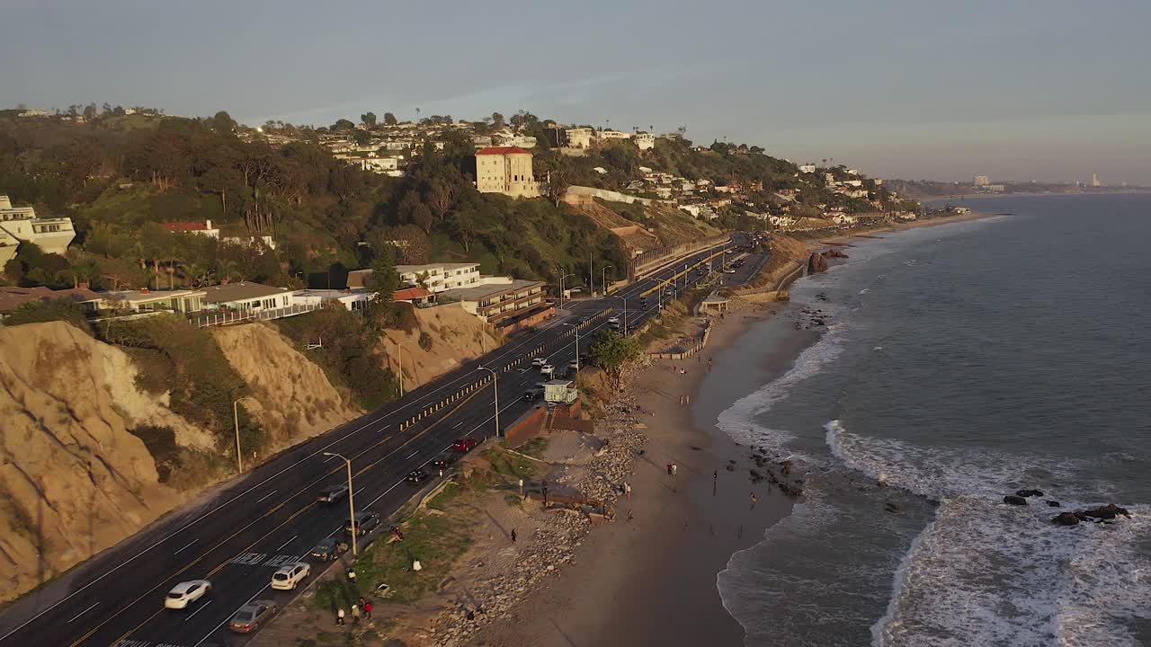 Cinematic aerial view of Traffic on California State Route one at sunset with Pacific Coastline and surrounding nature.