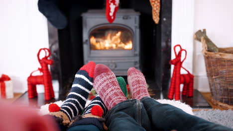 Low-section-of-couple-wearing-Christmas-socks-relaxing-in-front-of-fireplace,-detail